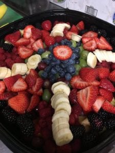 A large fruit salad with blueberries, bananas, grapes, strawberries and blackberries