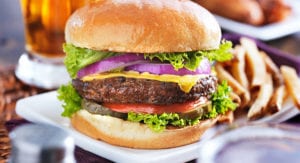 Large cheeseburger with lettuce, red onions and tomato with french fries